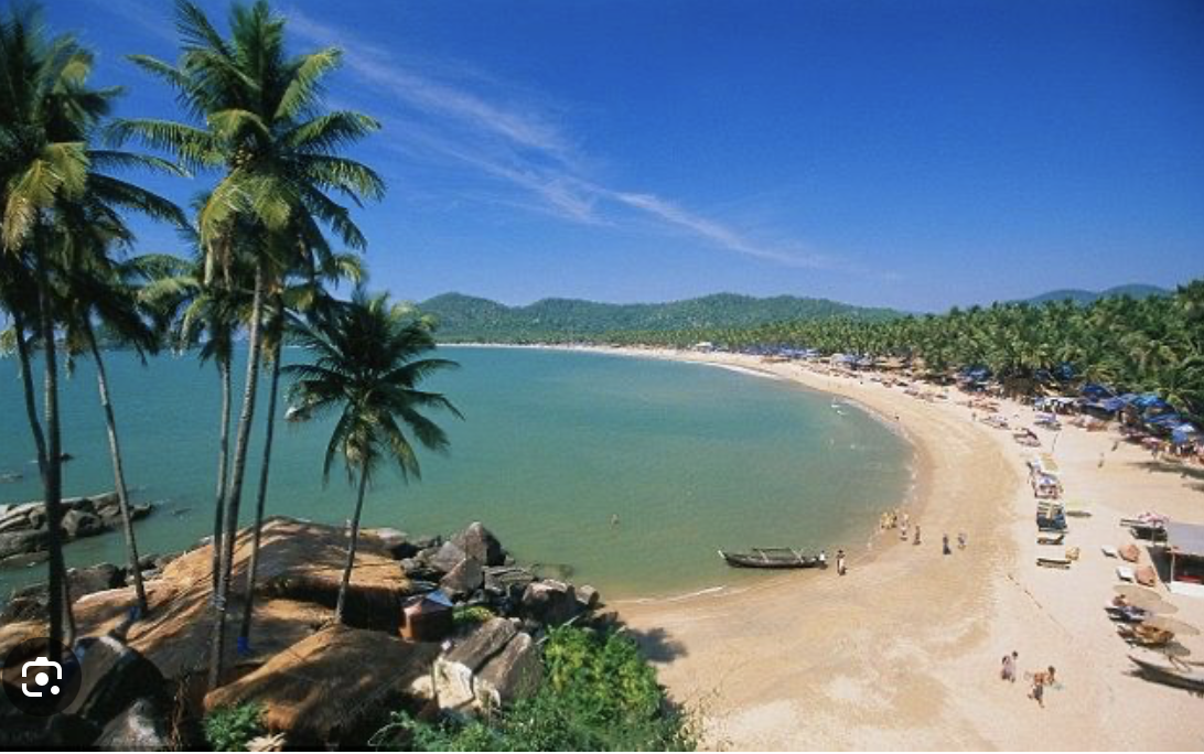 Elevated view across Patnem Beach from the rocky headland, palm trees and beach shacks along the bay